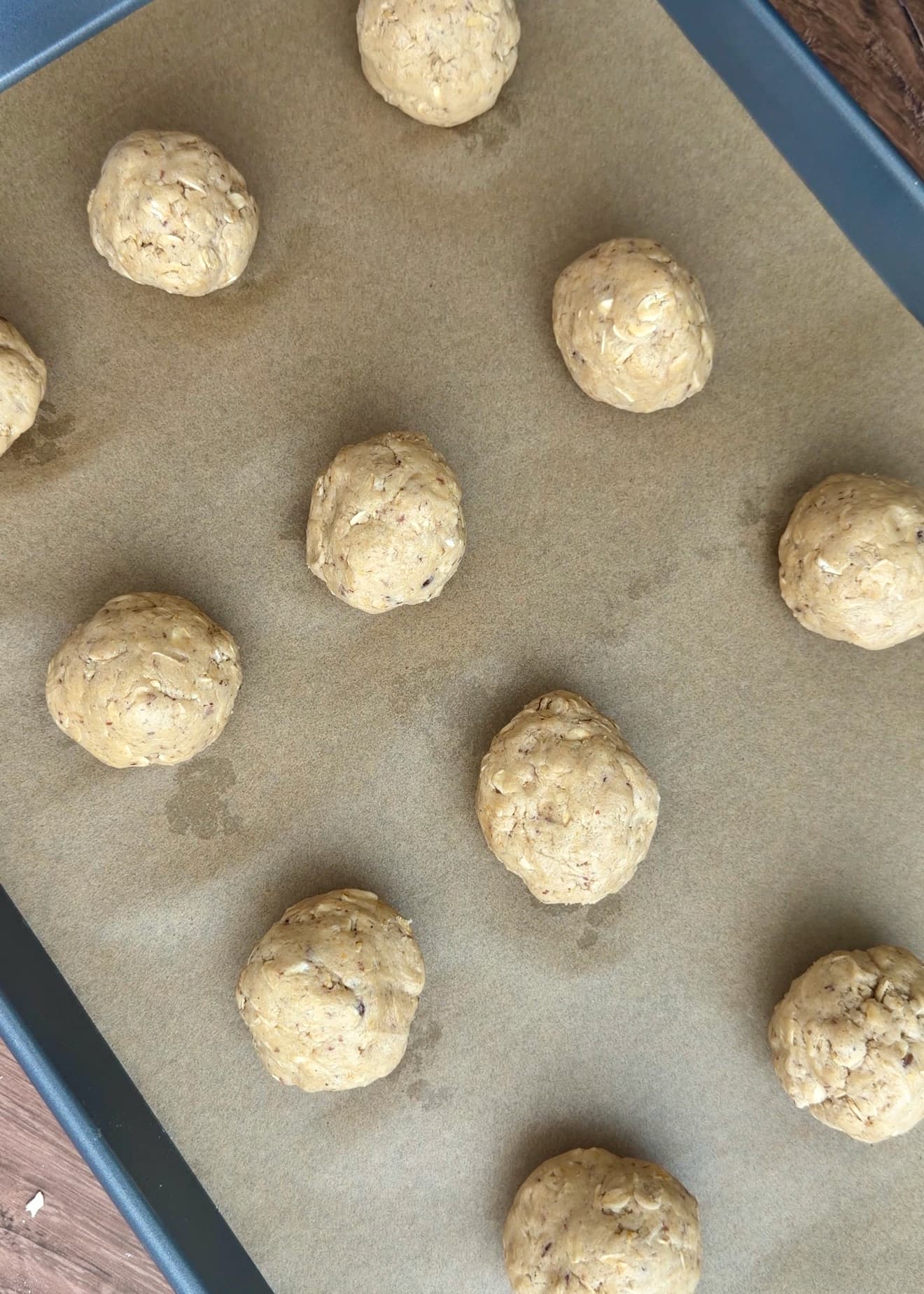 Rounded oatmeal dough portions spaced on a parchment-lined baking sheet