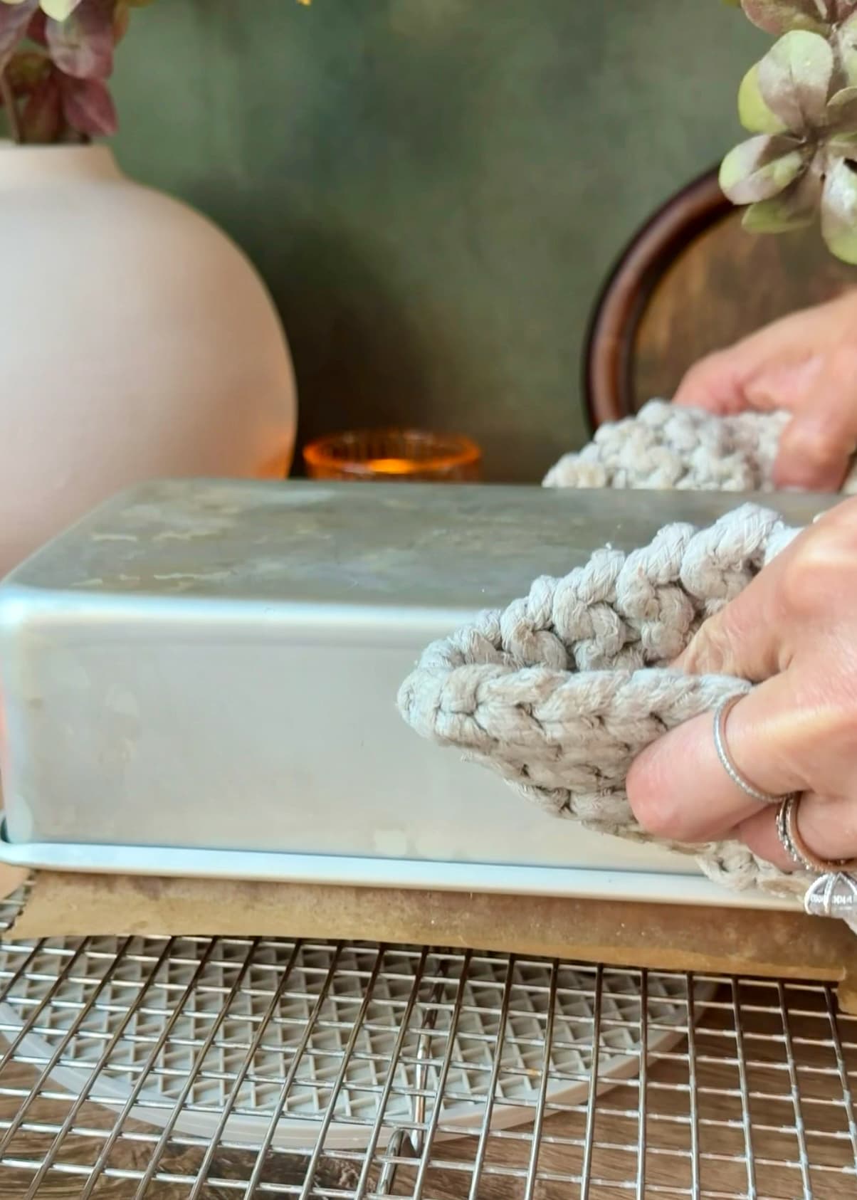 Hands in oven mitts holding an inverted loaf pan over a rack