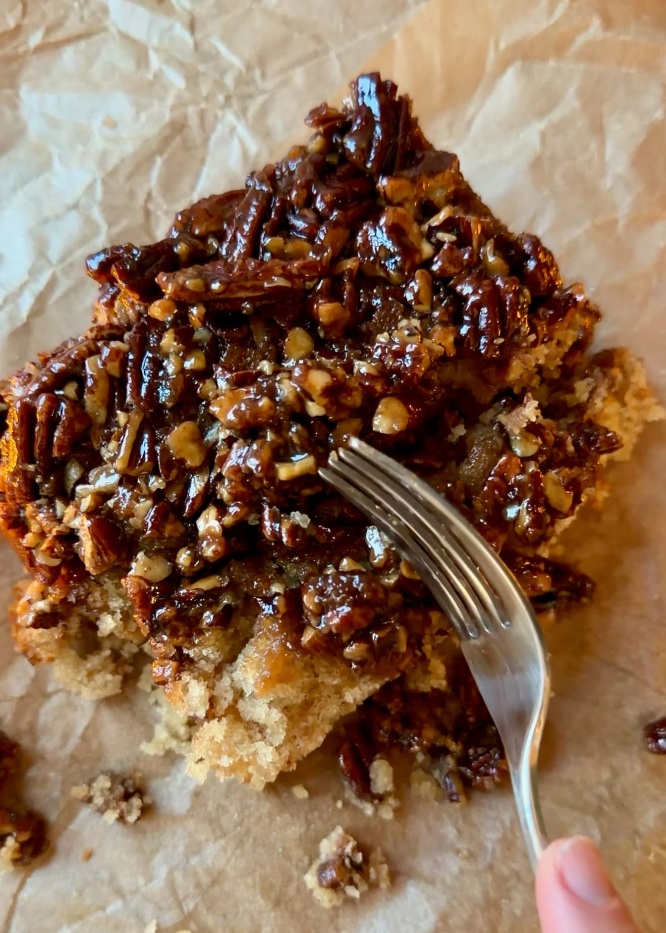 A fork resting on a slice with glossy caramelized pecans