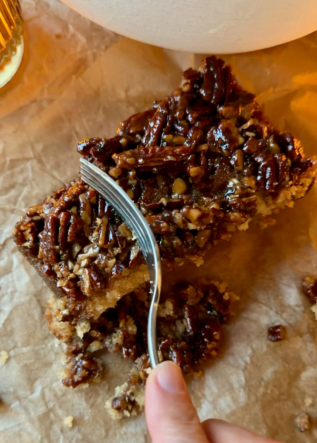 A fork beside a slice showing sticky pecans and the soft cake underneath