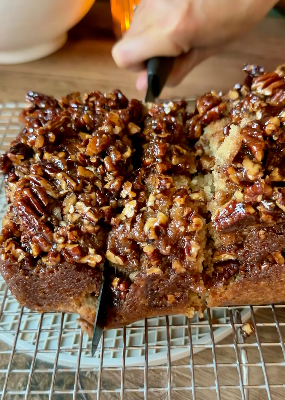 A knife cutting into the warm sticky pecan-topped loaf