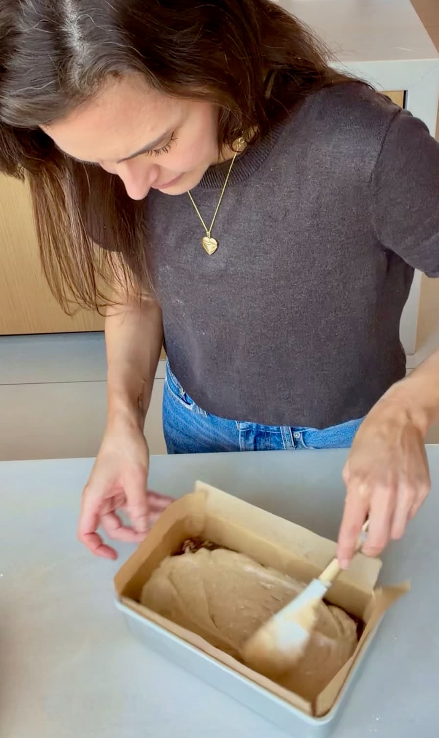 A spatula smoothing batter over the pecan mixture