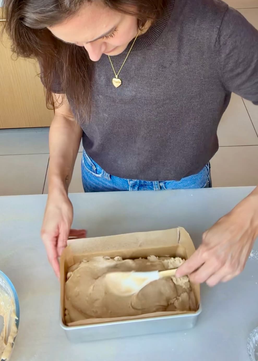 A spatula smoothing the upper layer of batter in the loaf pan