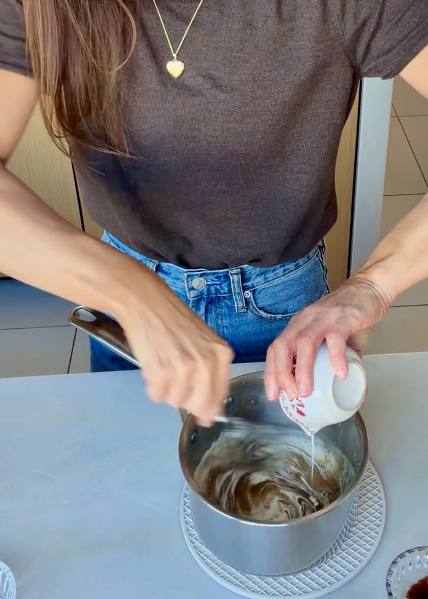 Angela stirring cream into the brown sugar topping in a saucepan