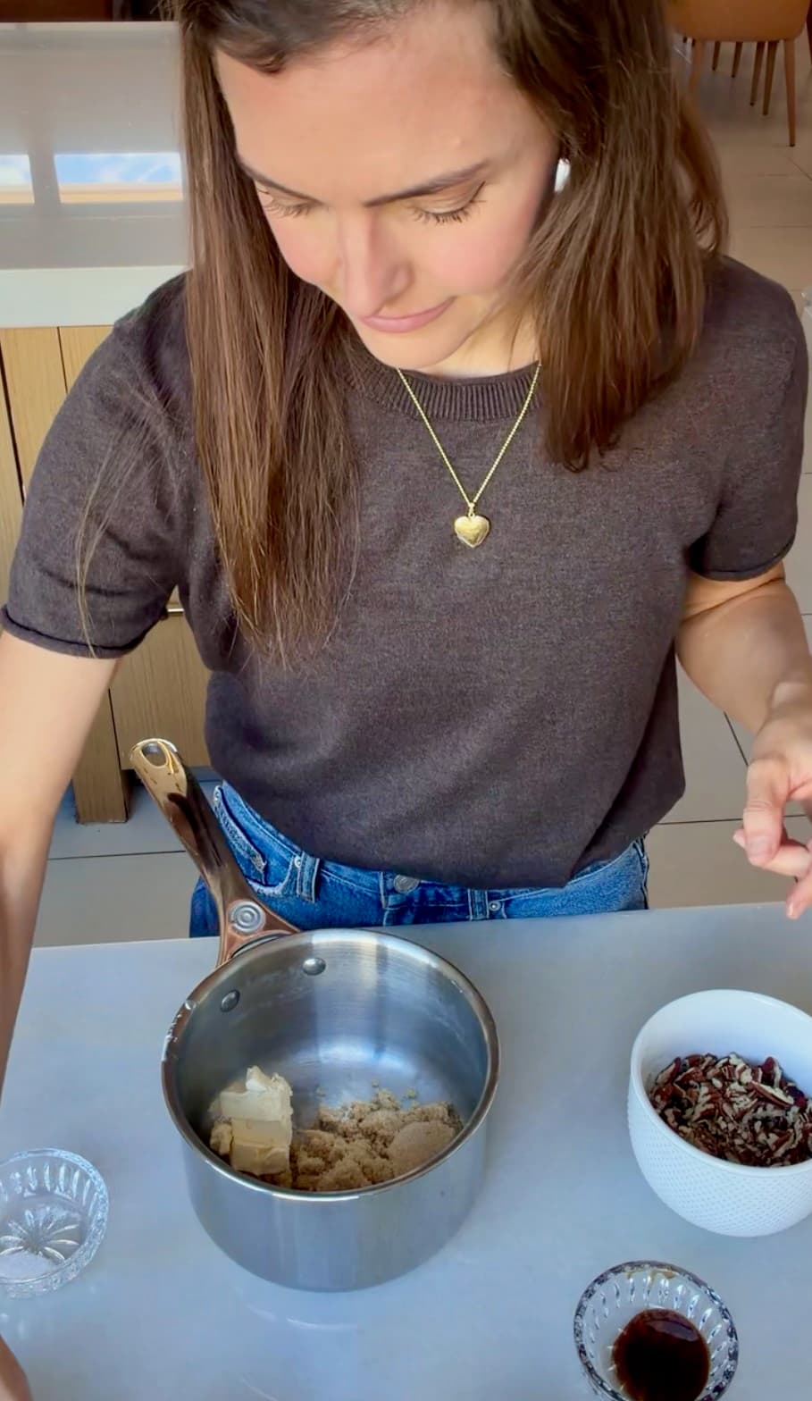Butter and brown sugar in a small saucepan beside a bowl of pecans