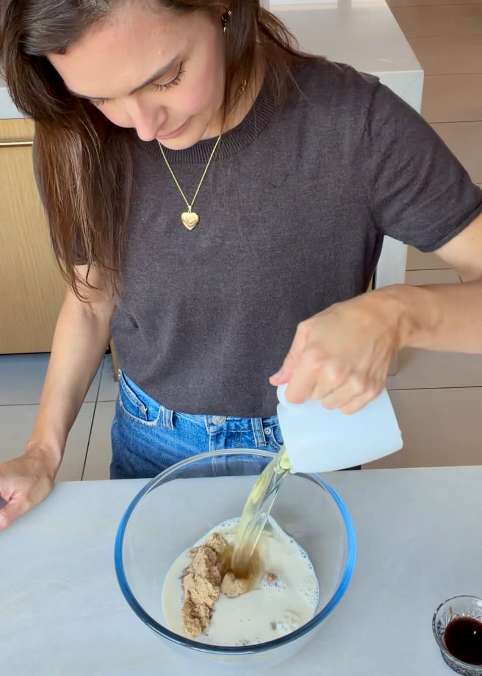 Oil pouring into a bowl of yogurt, sugars and other wet cake ingredients