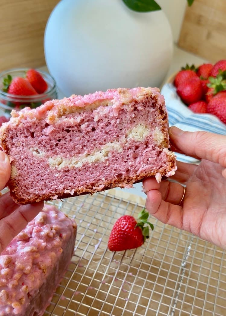 Slice of strawberry old-fashioned donut loaf showing its pink crumb and middle streusel layer