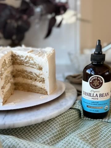 A sliced vanilla layer cake beside a bottle of Rising Star vanilla bean paste