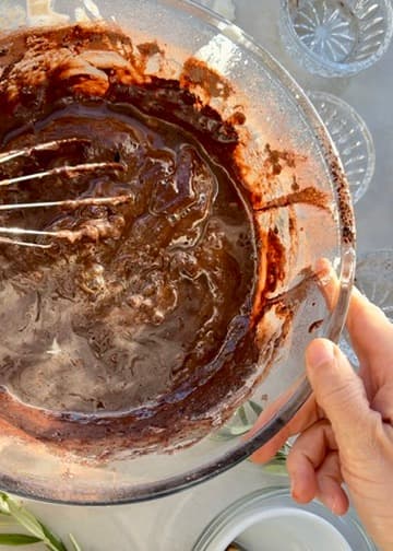 Glossy chocolate batter with liquid around the edge of the bowl