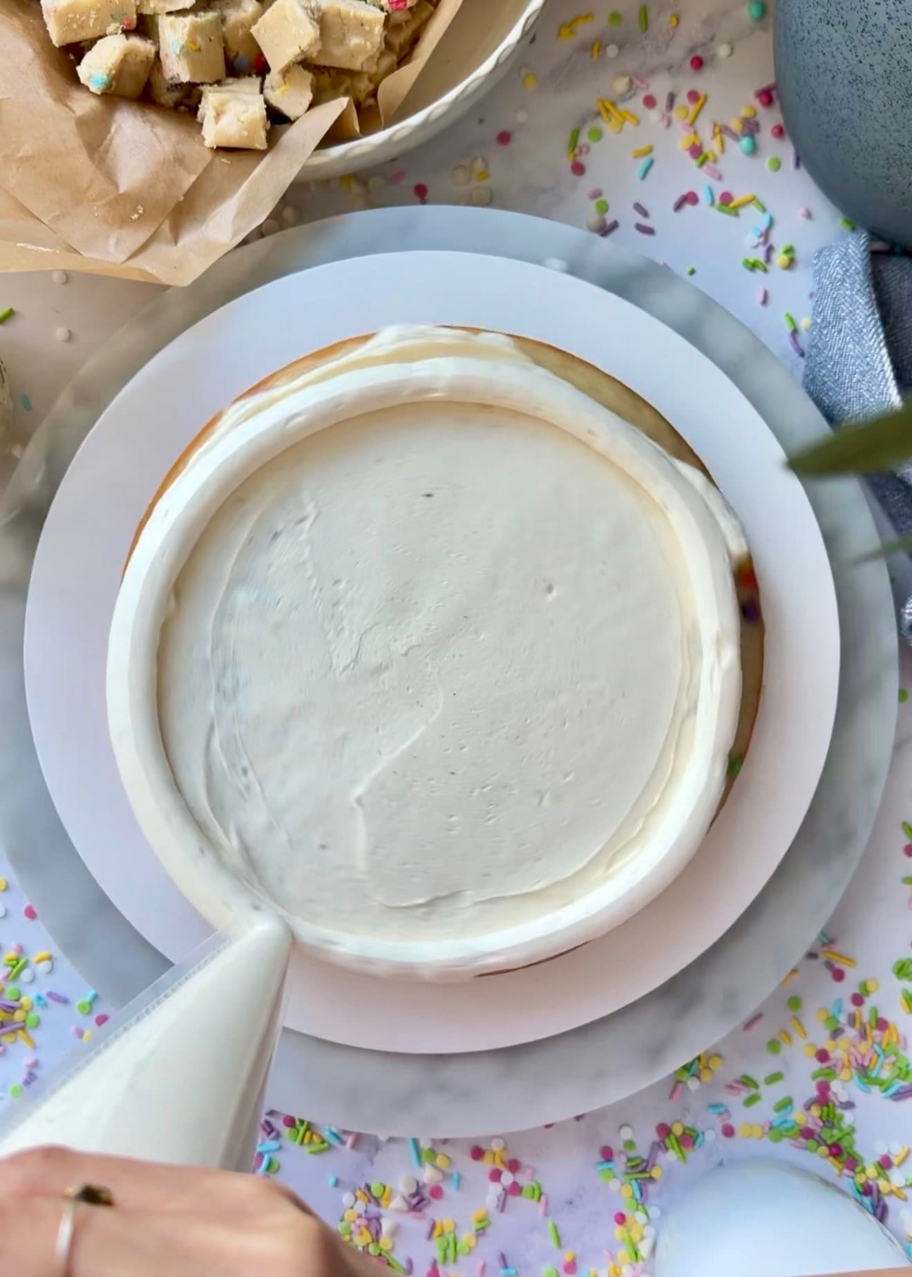 A piping bag completing the buttercream ring around the cake