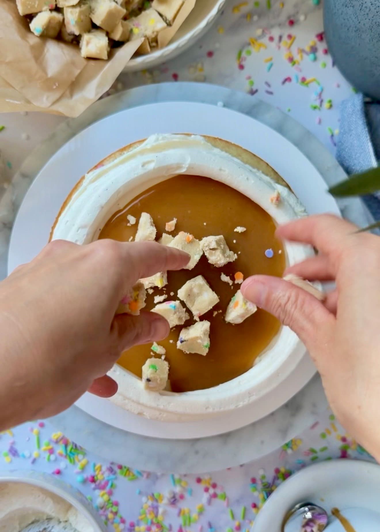 Hands scattering cookie-dough pieces over the lava