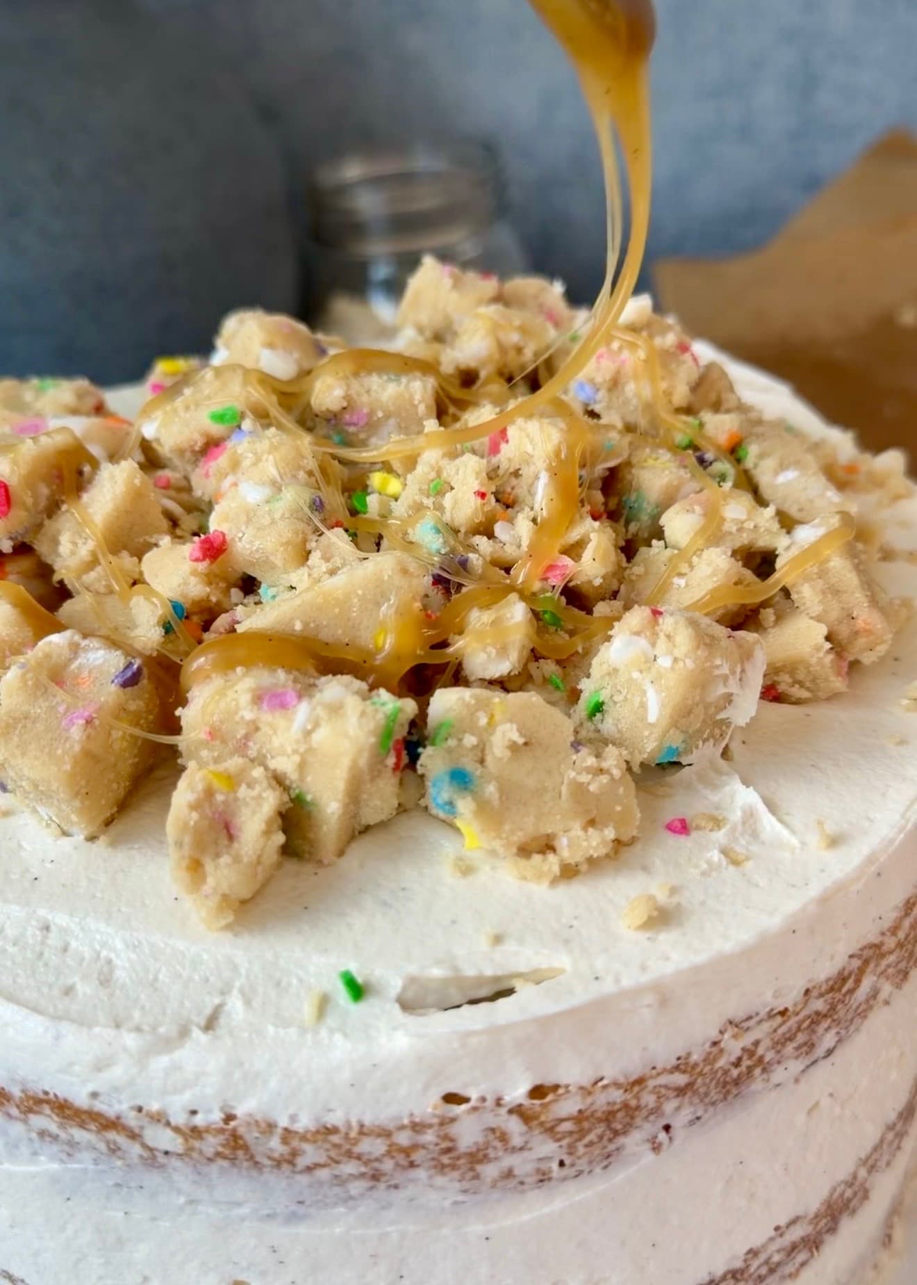 Blondie lava drizzling over cookie-dough pieces on the frosted cake