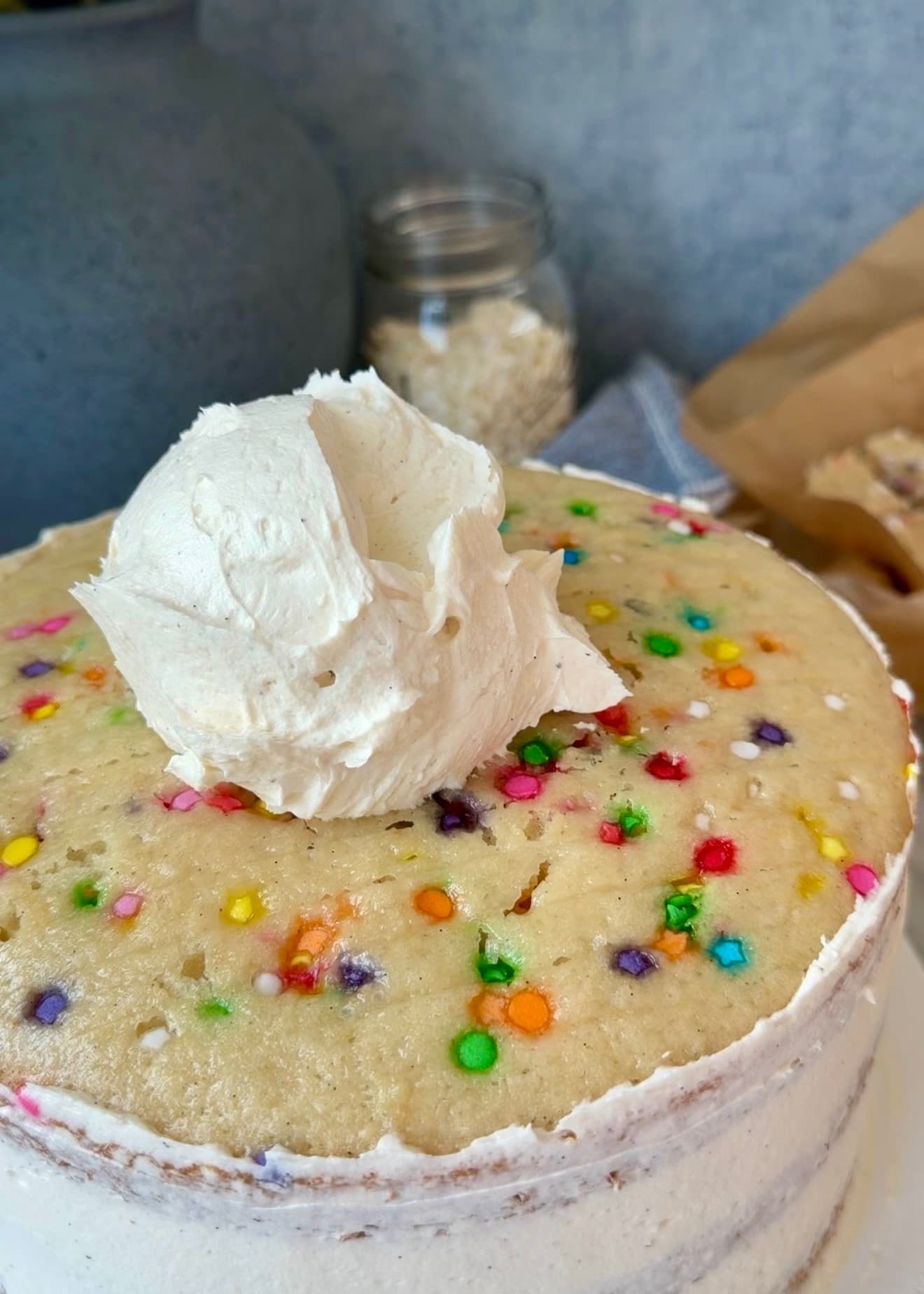 A scoop of buttercream on top of the cake after the sides are coated