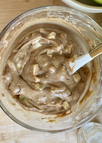 Finished spiced apple batter in a glass mixing bowl