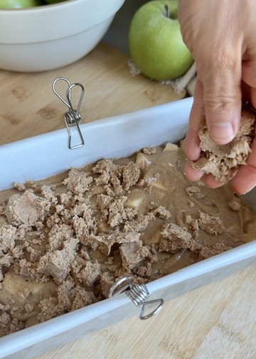 Cinnamon streusel being layered over apple donut loaf batter