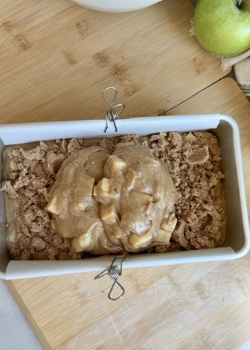 Second layer of apple batter being spread over cinnamon streusel