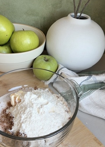 Cinnamon streusel ingredients in a glass bowl beside Granny Smith apples