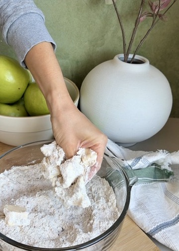 Cold butter being worked into cinnamon streusel ingredients