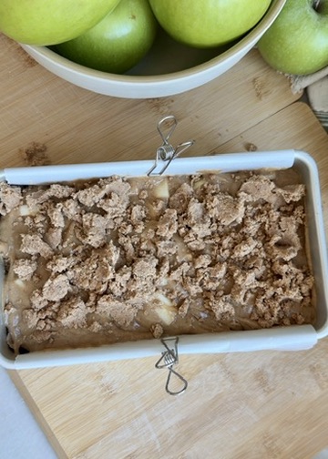 Apple fritter donut loaf batter covered with cinnamon streusel before baking