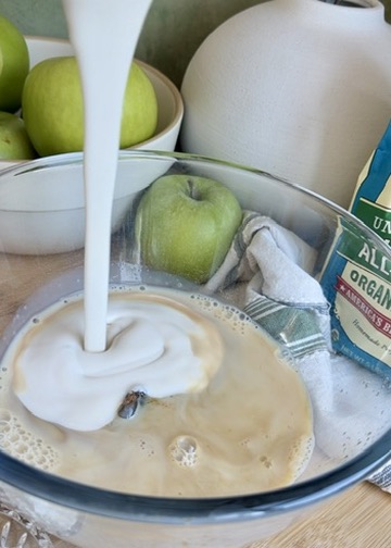 Milk being poured into the wet ingredients for apple fritter donut loaf