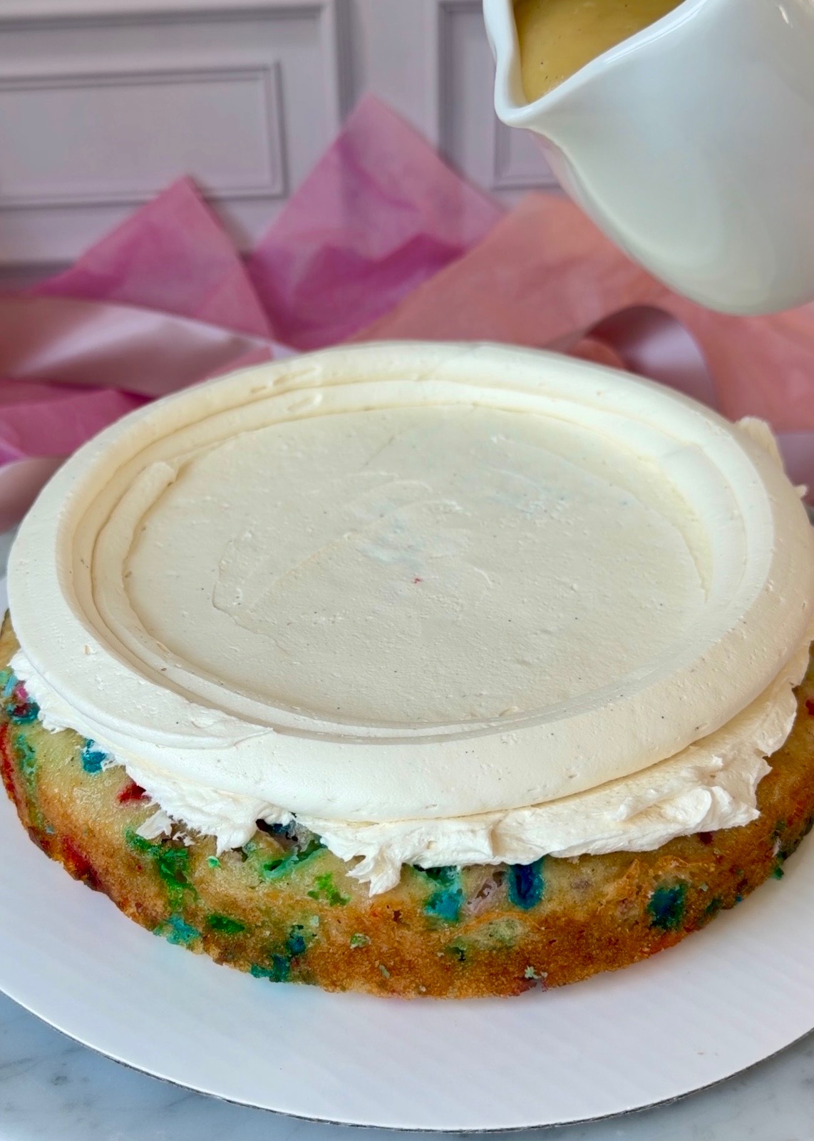 Tall vanilla buttercream dam piped around a funfetti cake layer