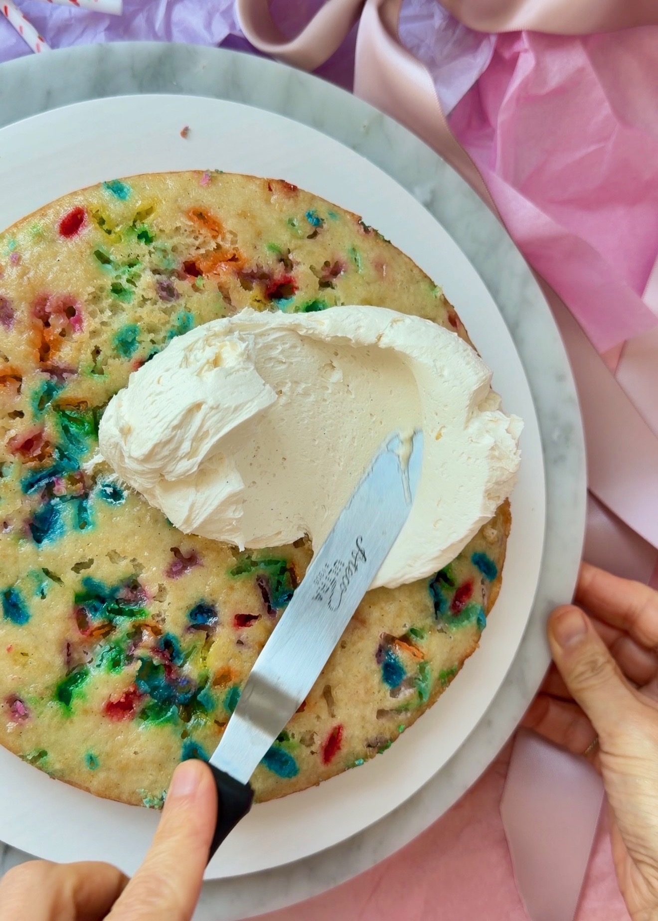 Vanilla buttercream spread over a funfetti cake layer