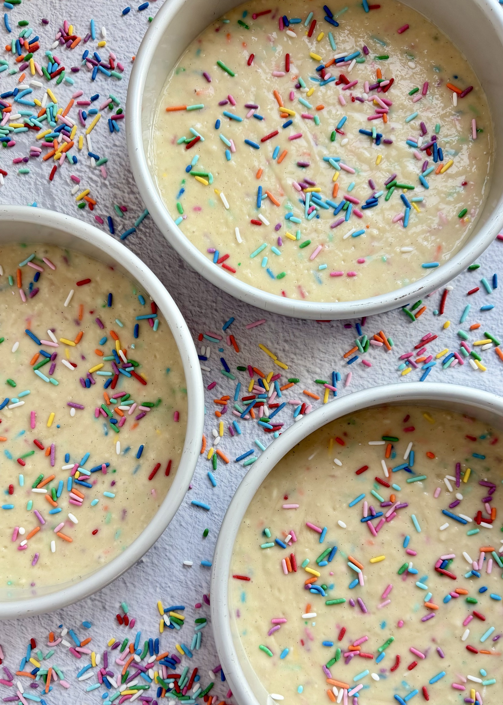 Funfetti cake batter divided among three round cake pans