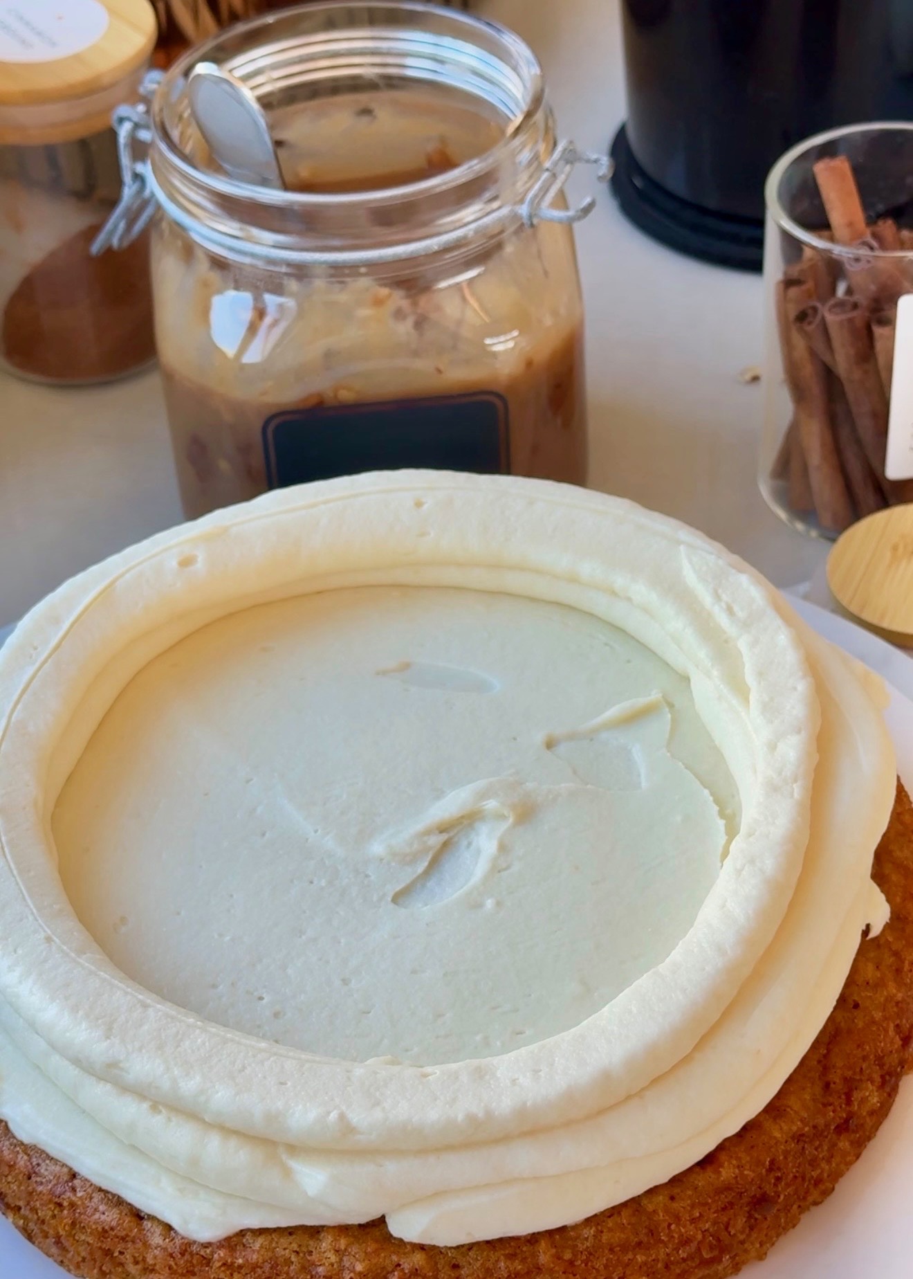 Tall cheesecake frosting dam piped around a carrot cake layer