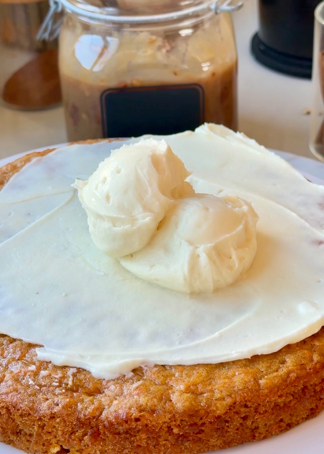 Silky cheesecake frosting spread over a carrot cake layer