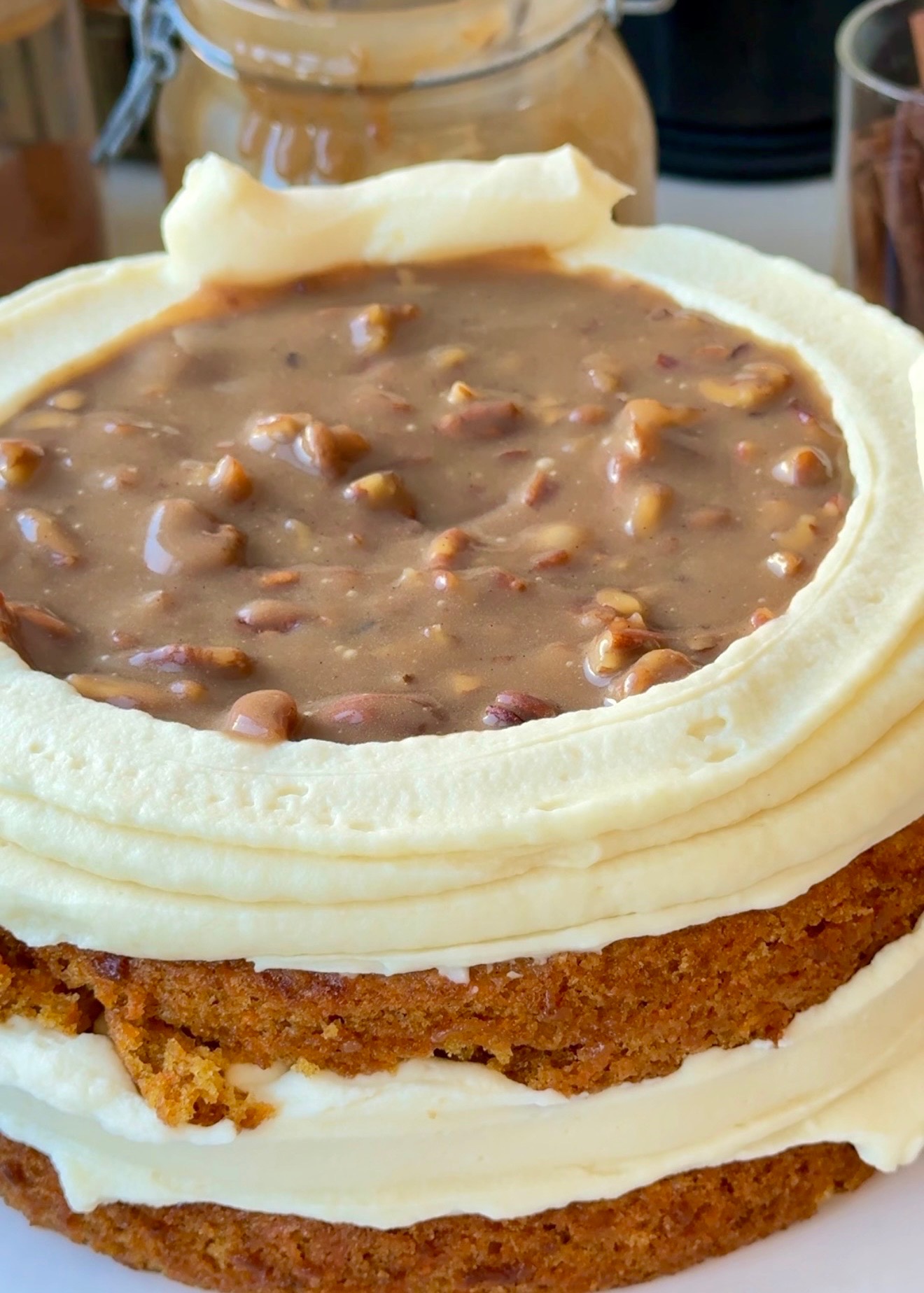 Carrot cake layers stacked with cheesecake frosting and pecan praline