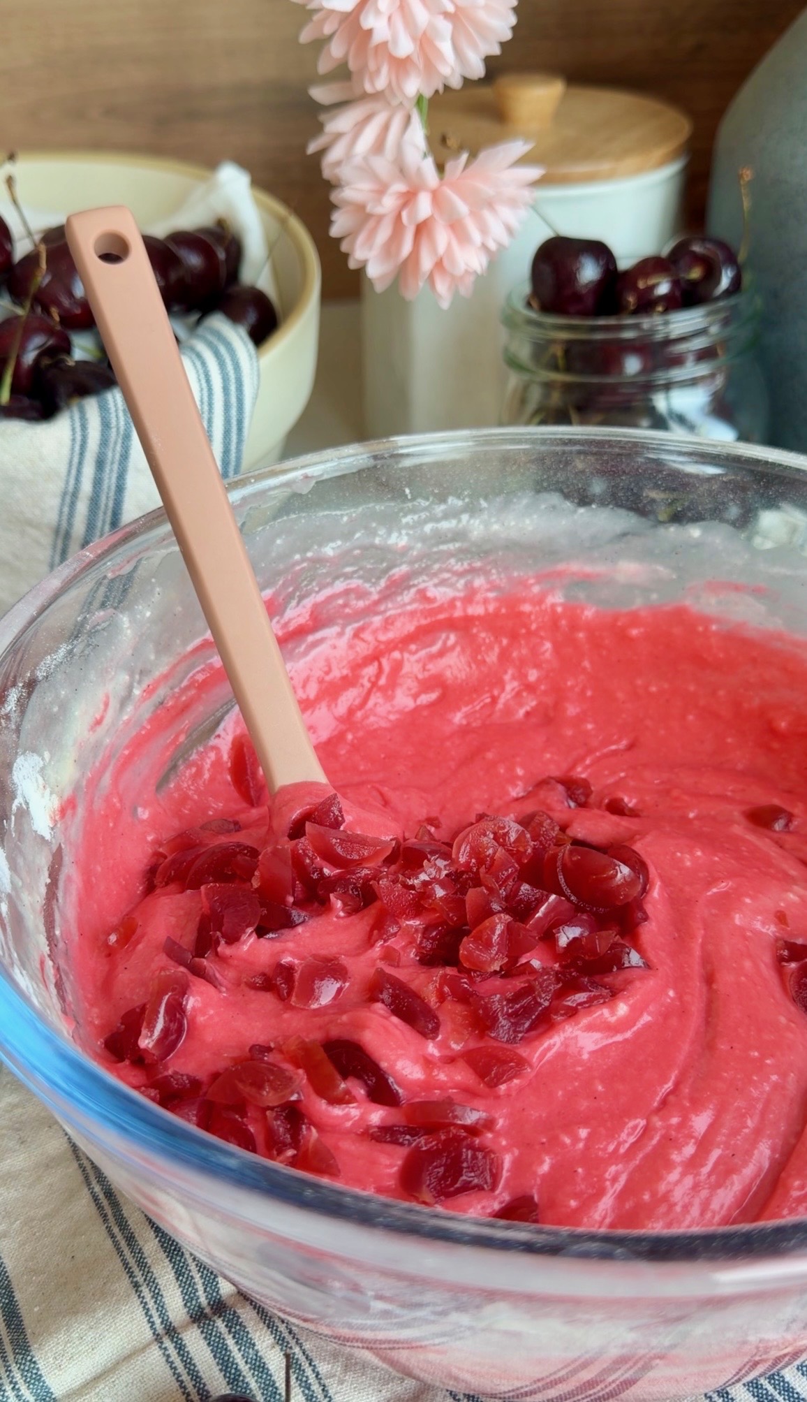 Finely chopped maraschino cherries being folded into bright red donut loaf batter