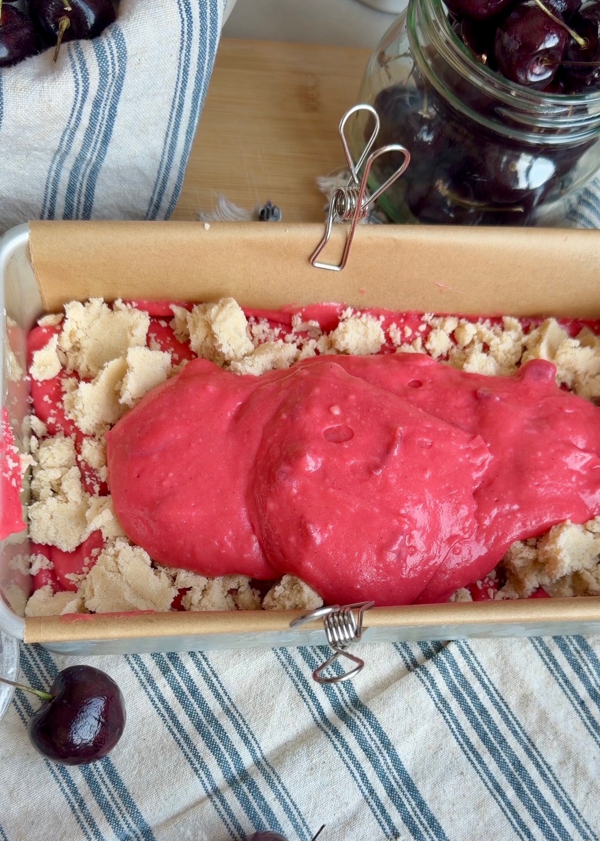 Cherry donut loaf batter layered with buttery streusel in a parchment-lined pan