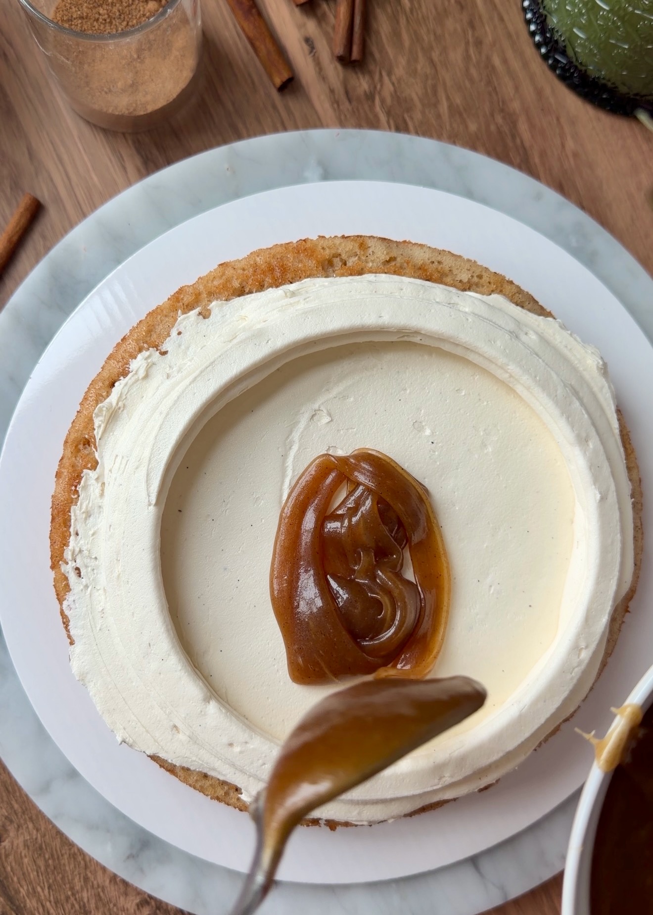 Thick cinnamon roll filling spooned inside a tall frosting dam