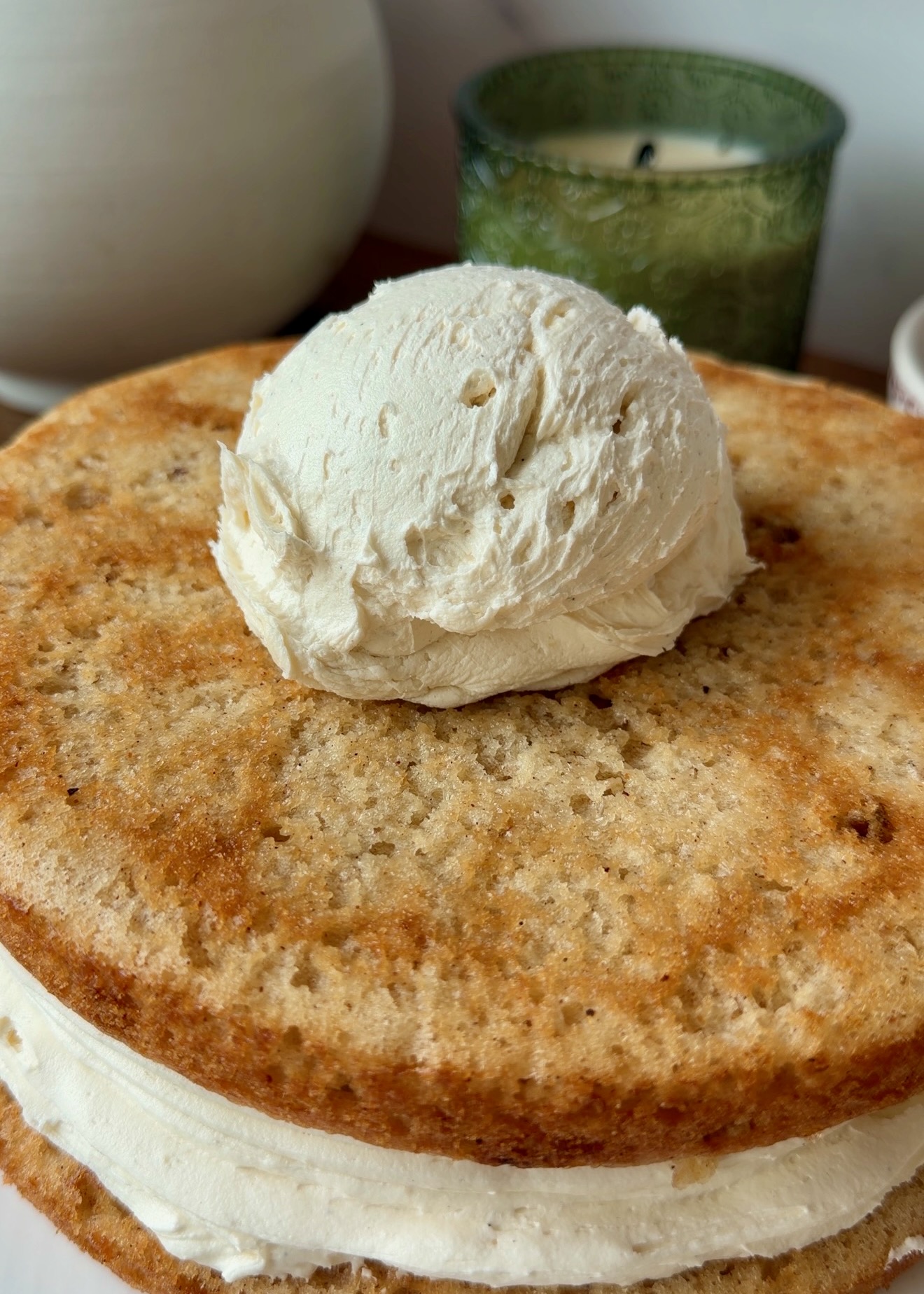 Vanilla frosting being added to a cinnamon cake layer
