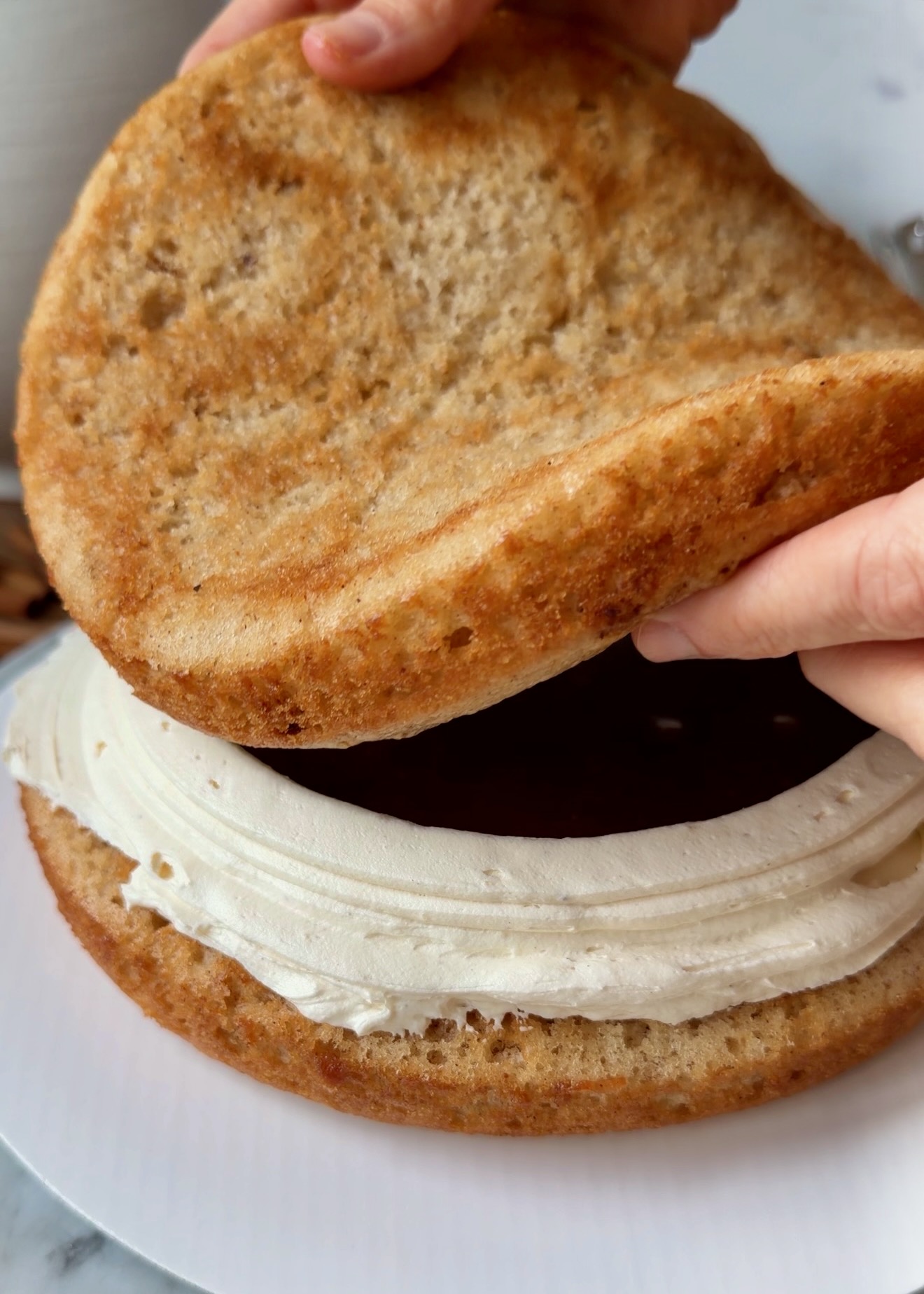 Cake layer being placed over cinnamon filling and frosting