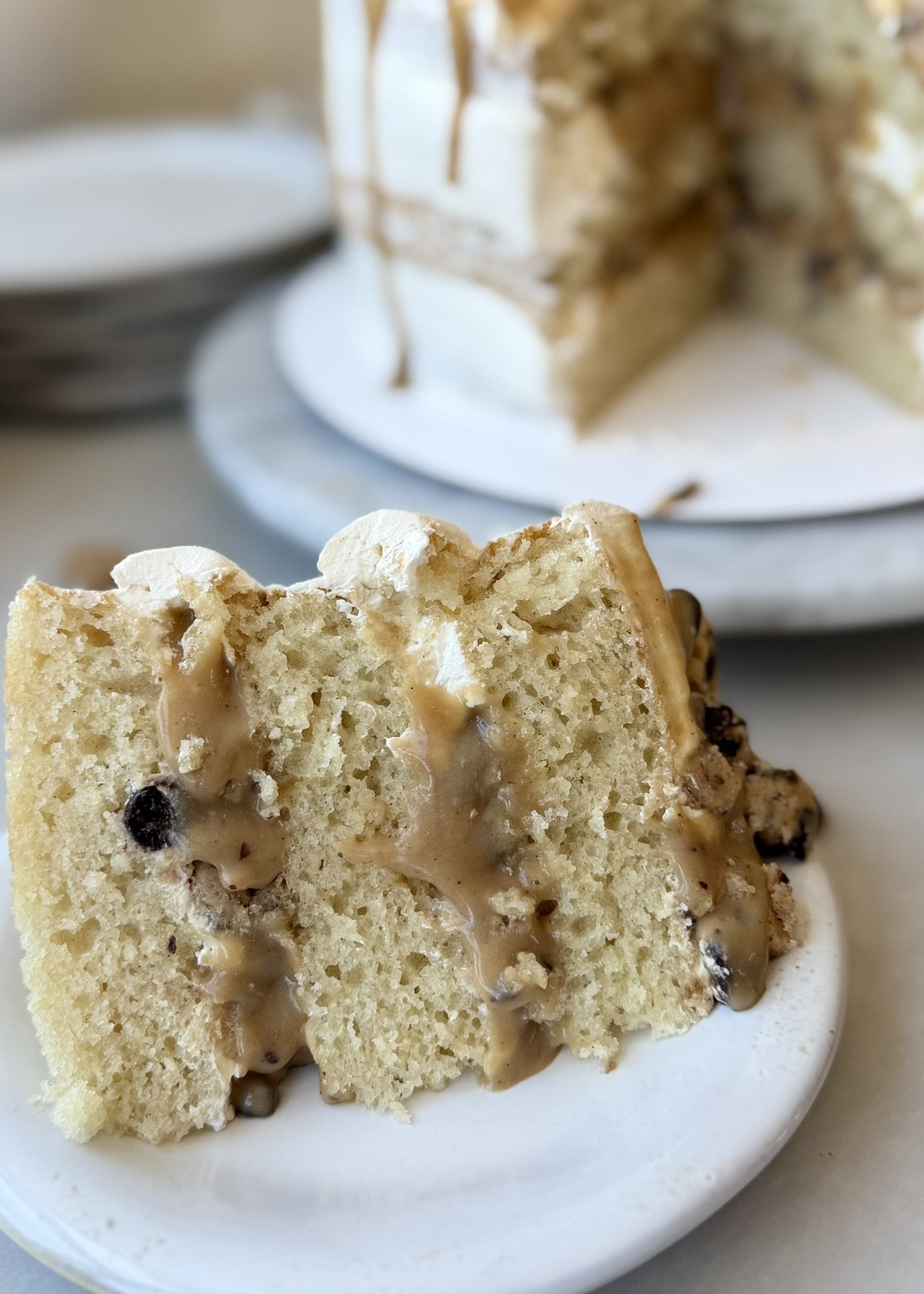 A slice of cookie dough lava cake with thick cookie dough filling flowing between vanilla cake layers