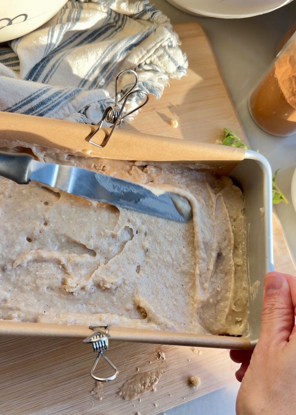 French toast donut loaf batter being spread into a parchment-lined loaf pan