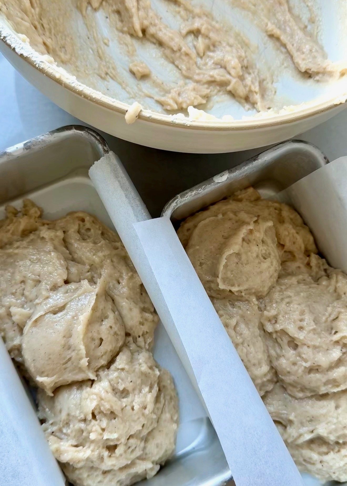 Rested gluten-free donut loaf batter divided between parchment-lined loaf pans