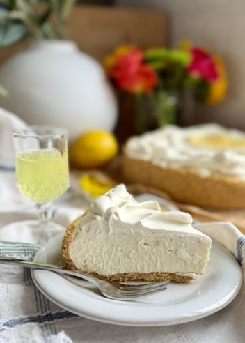Plated Limoncello Cheesecake Mousse slice with the finished cheesecake behind it