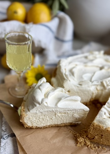 Limoncello Cheesecake Mousse slice beside a glass of limoncello and fresh lemons