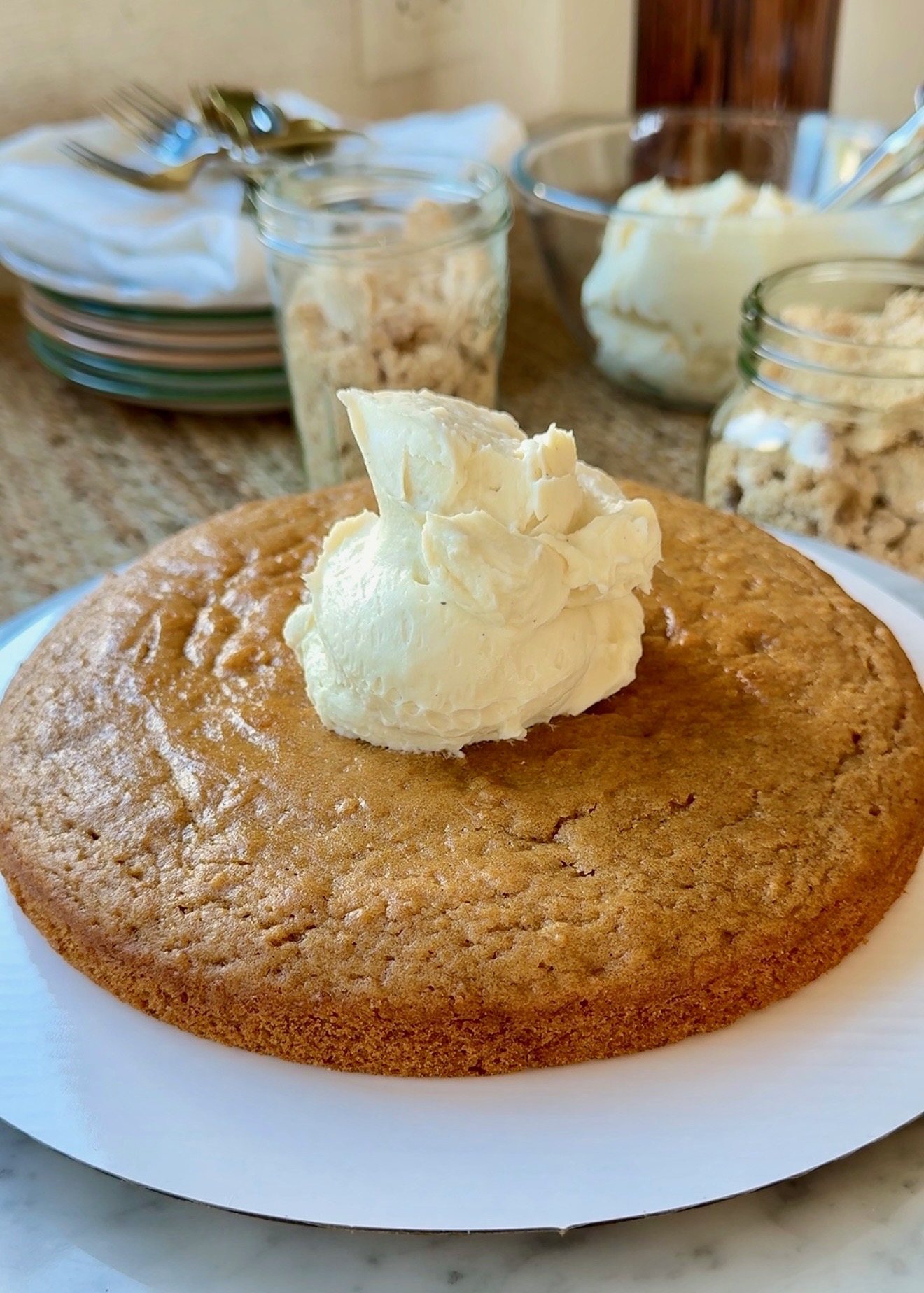 Vanilla buttercream spread over an oatmeal cake layer during assembly