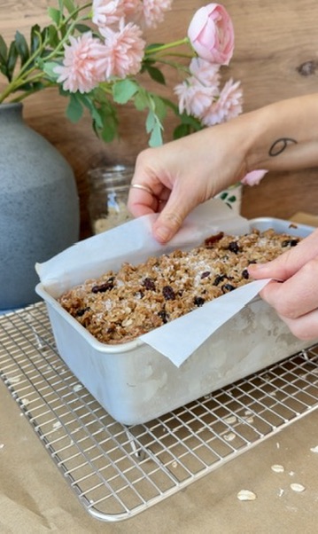 Freshly baked Oatmeal Cookie Donut Loaf being lifted from its loaf pan with parchment paper