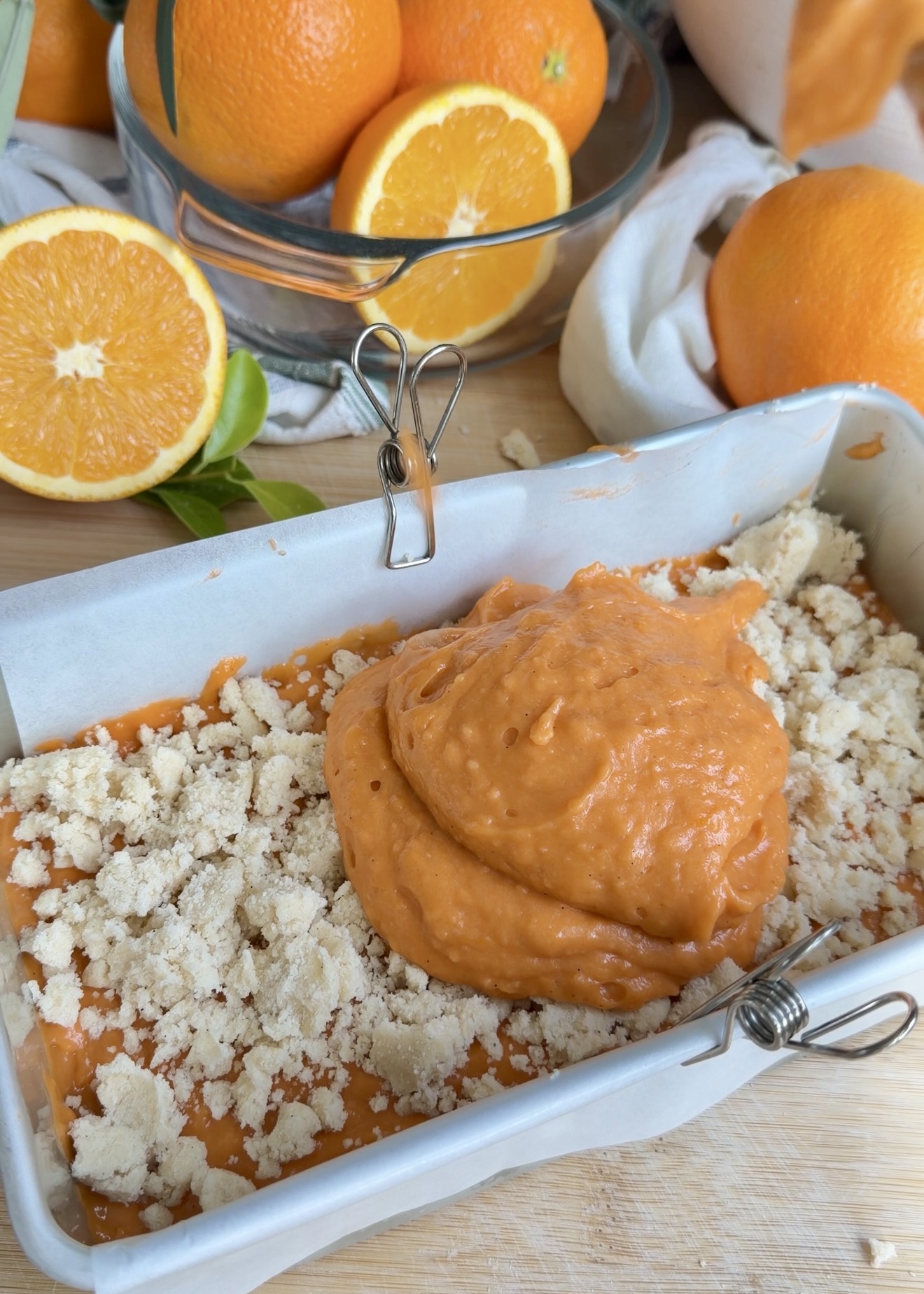 Orange loaf batter being layered over large pieces of streusel