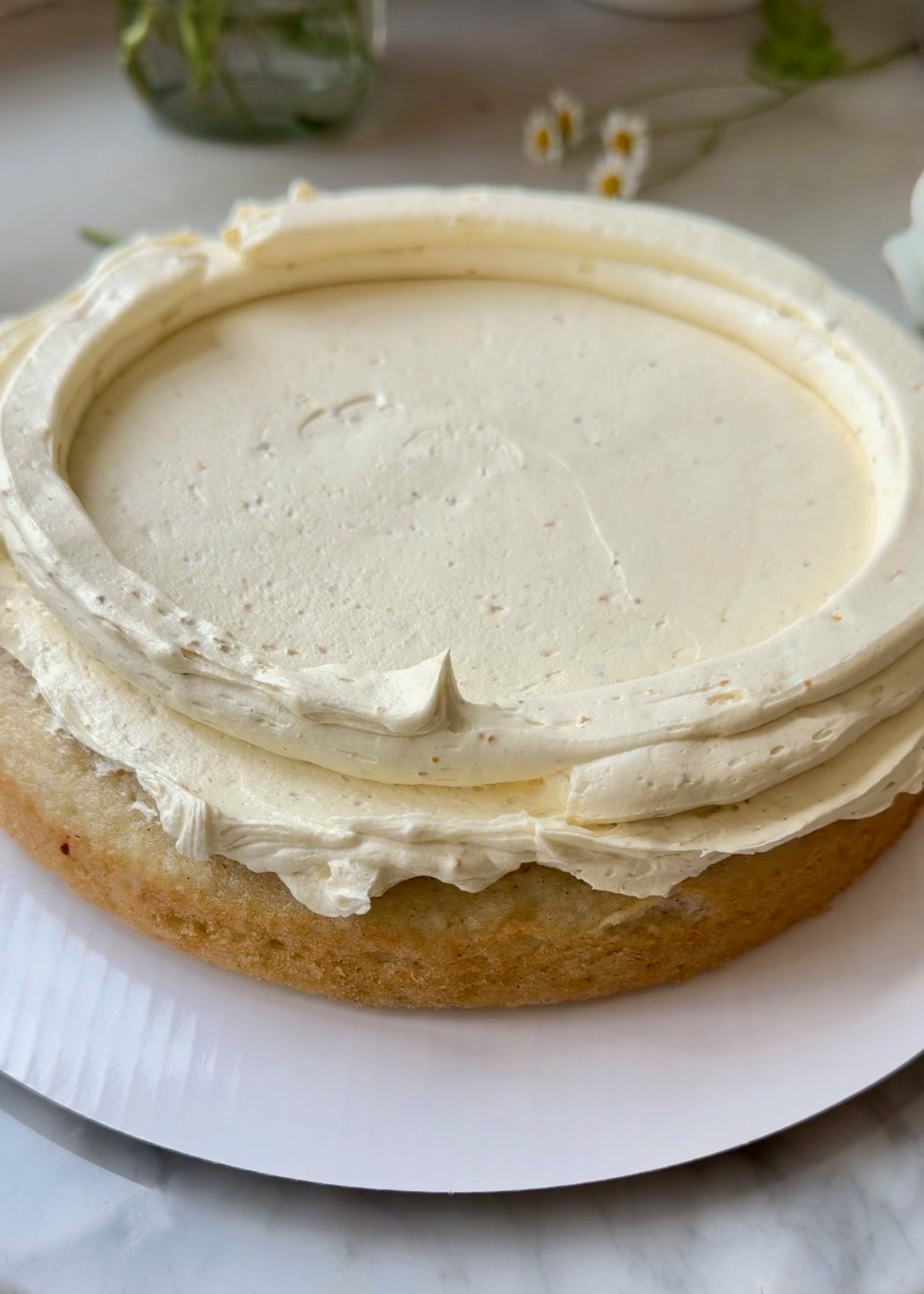 Pistachio buttercream dam piped around a vanilla cake layer