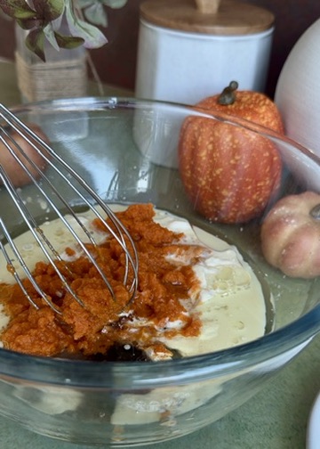 Pumpkin puree, yogurt, milk, oil, and sugar in a glass mixing bowl