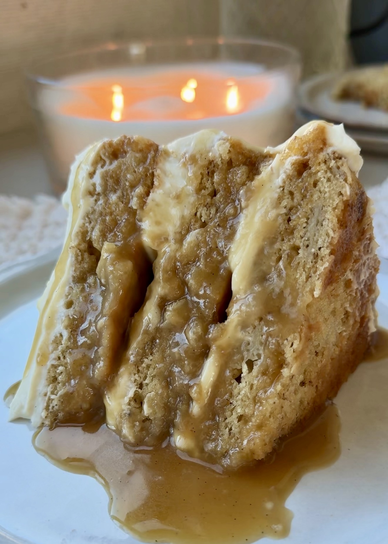 Lifted slice of banana cheesecake cake showing caramel and frosting between the layers
