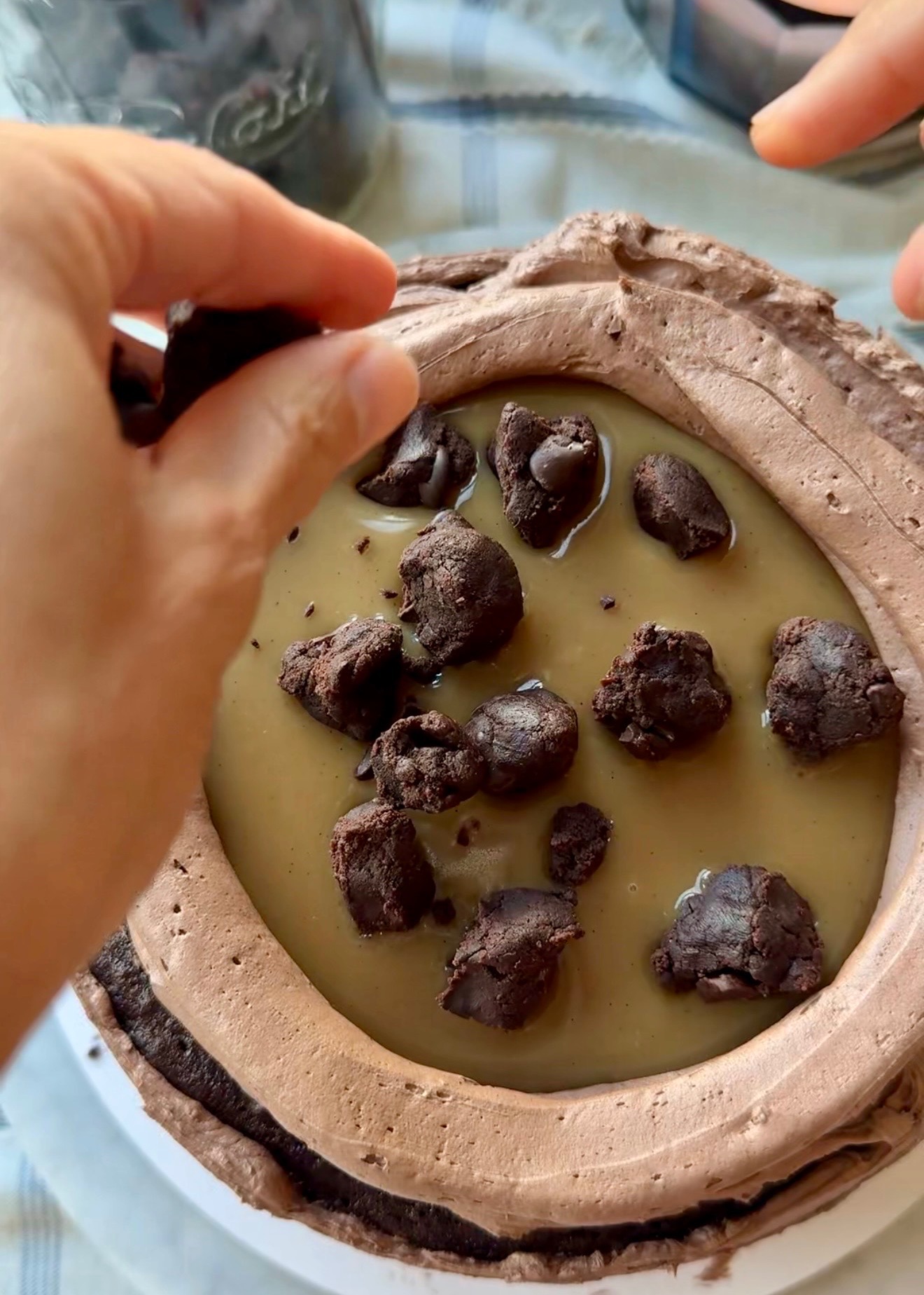 Raw brownie batter squares being added over salted caramel filling