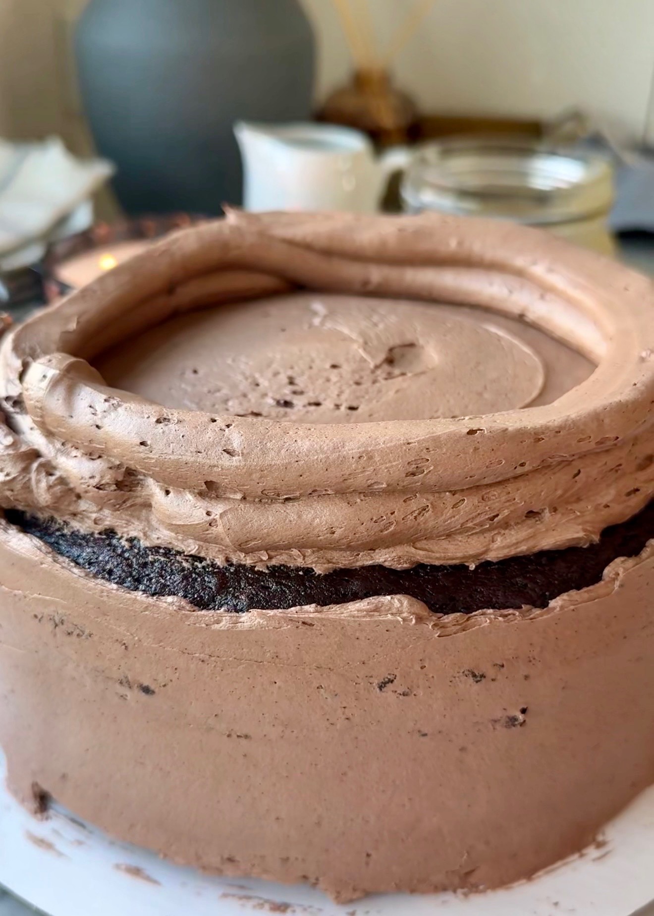 Tall chocolate buttercream dam piped around a chocolate cake layer