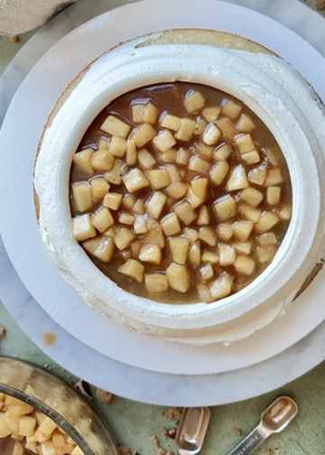 Apple pie filling spread inside a tall vanilla buttercream dam