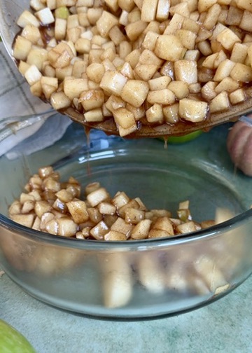 Skillet apple pie filling being transferred to a bowl to cool